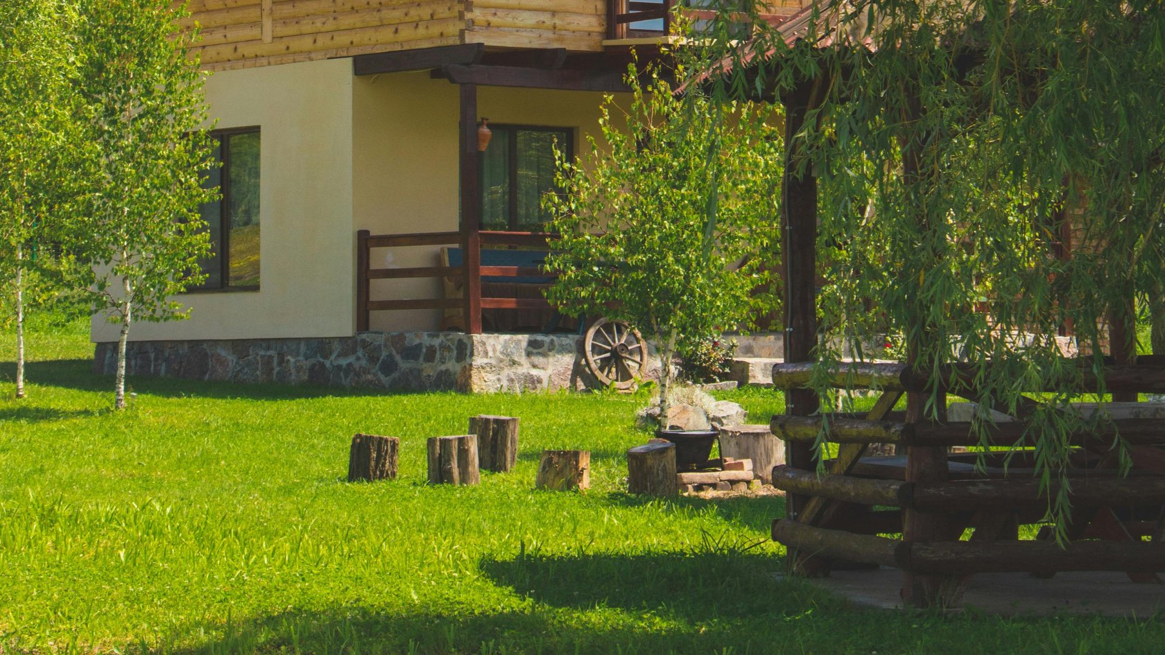 Maison en bois avec jardin verdoyant, entouré d'arbres et de rondins, solution anti-taupe, piège à taupe, détaupeur, detaupeur, quicktaupe, se debarrasser des taupes, tuer les taupes, éliminer les taupes, faire partir les taupes, faire fuir les taupes, anti-taupe.